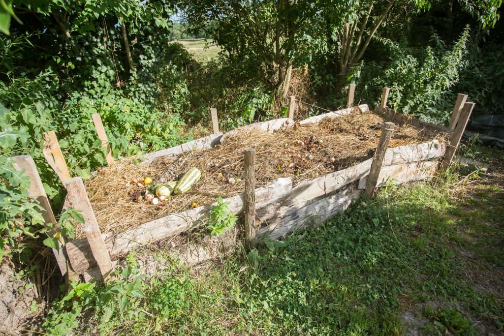 tas de compost retenu à l'aide de planches au jardin