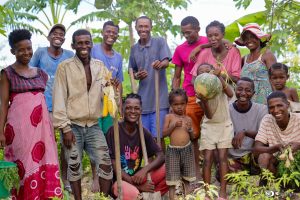 Photo de groupe des membres de la communauté travaillant avec l'ONG La Forêt Retrouvée. On les voit souriants, tenants des outils de jardin et quelques unes de leurs premières récoltes.