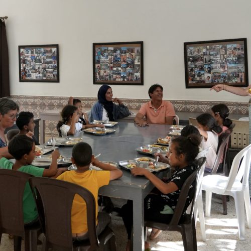 Photos de groupe montrant les enfants du Centre Fiers et Forts entrain de déjeuner en compagnie de la fondatrice du centre, Madou.